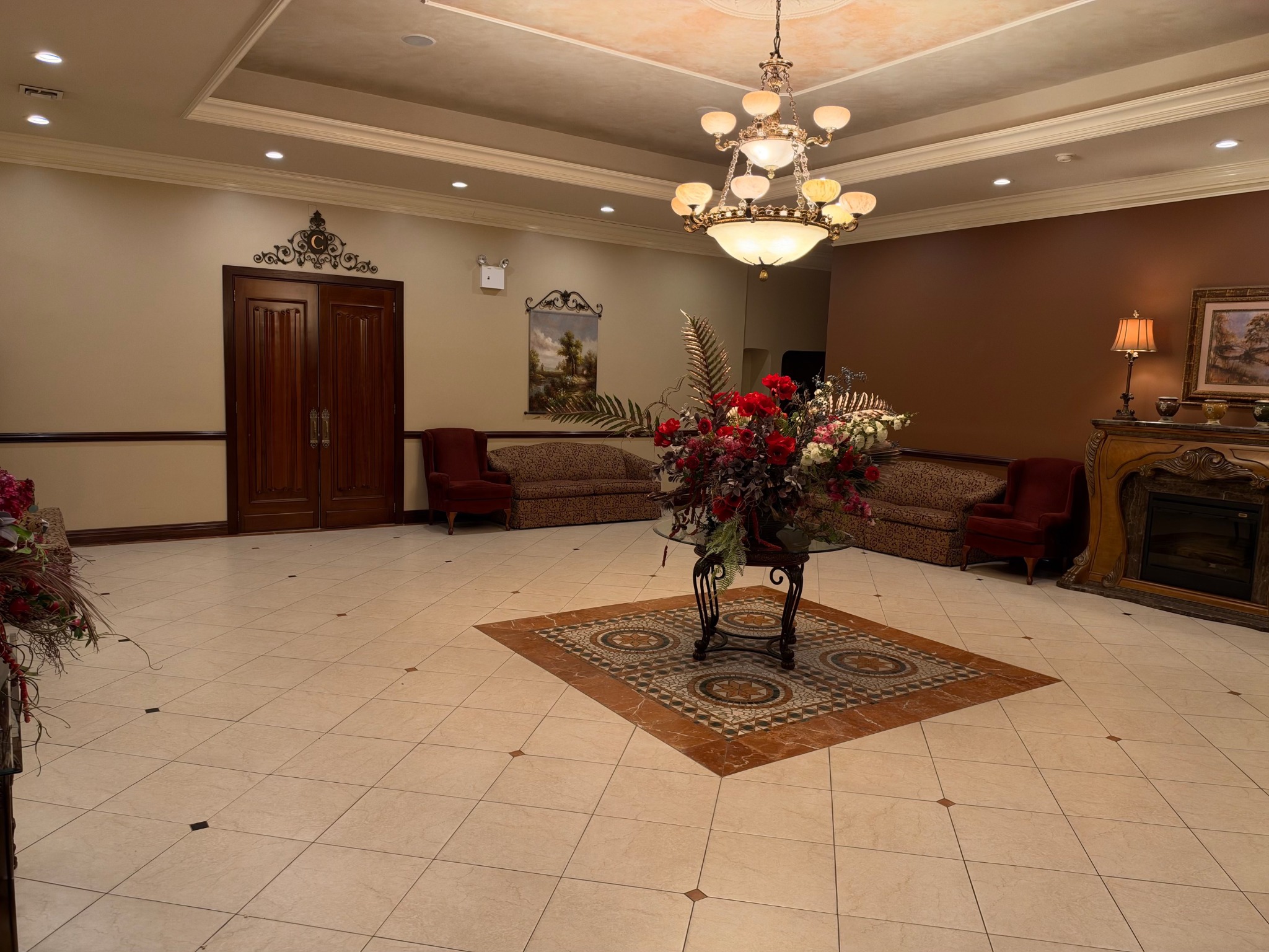 The main lobby with a chandelier, floral centerpiece, fireplace, and seating for families.