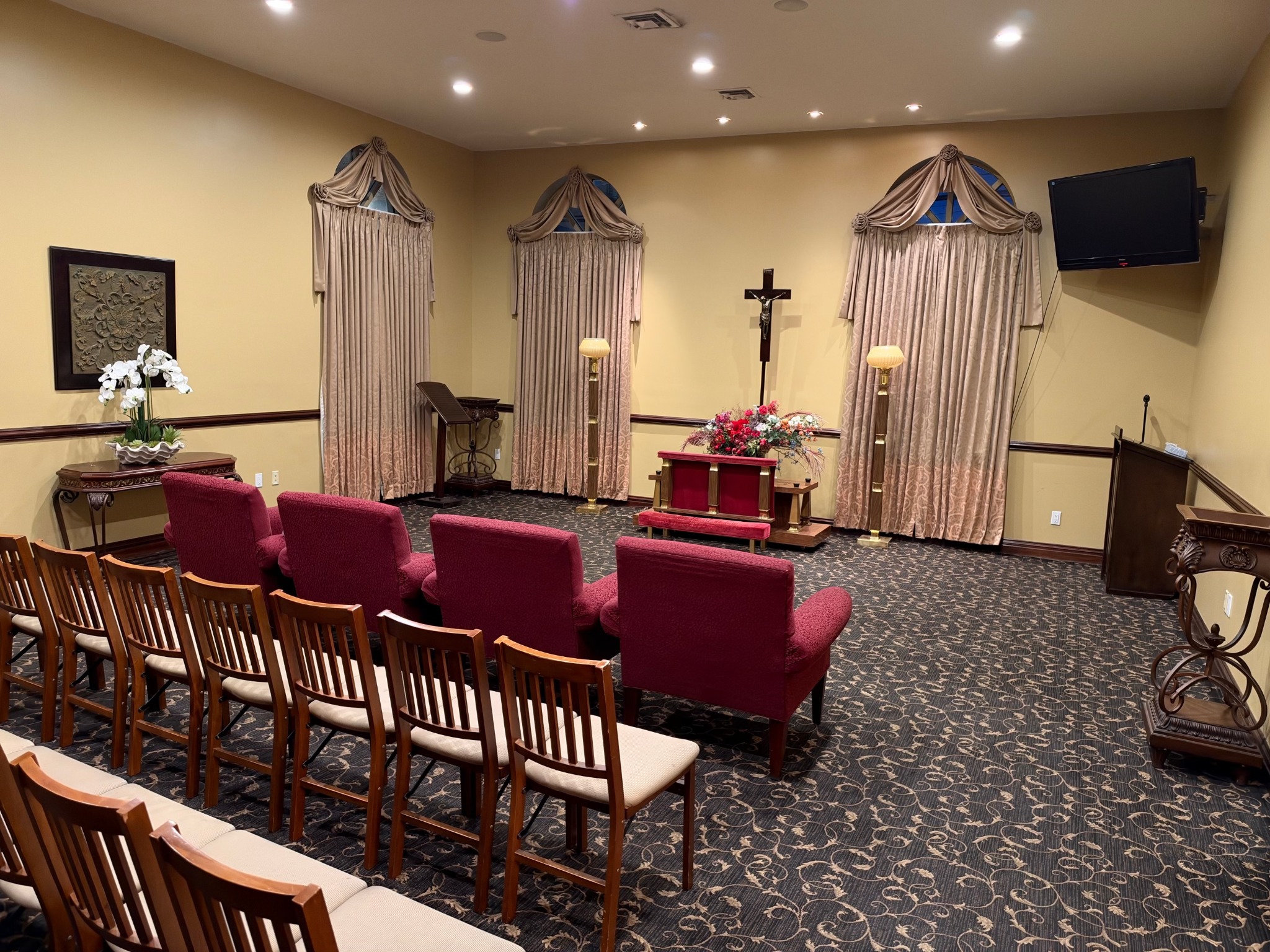 A full view of the chapel with rows of seating, a lectern, and a floral arrangement.