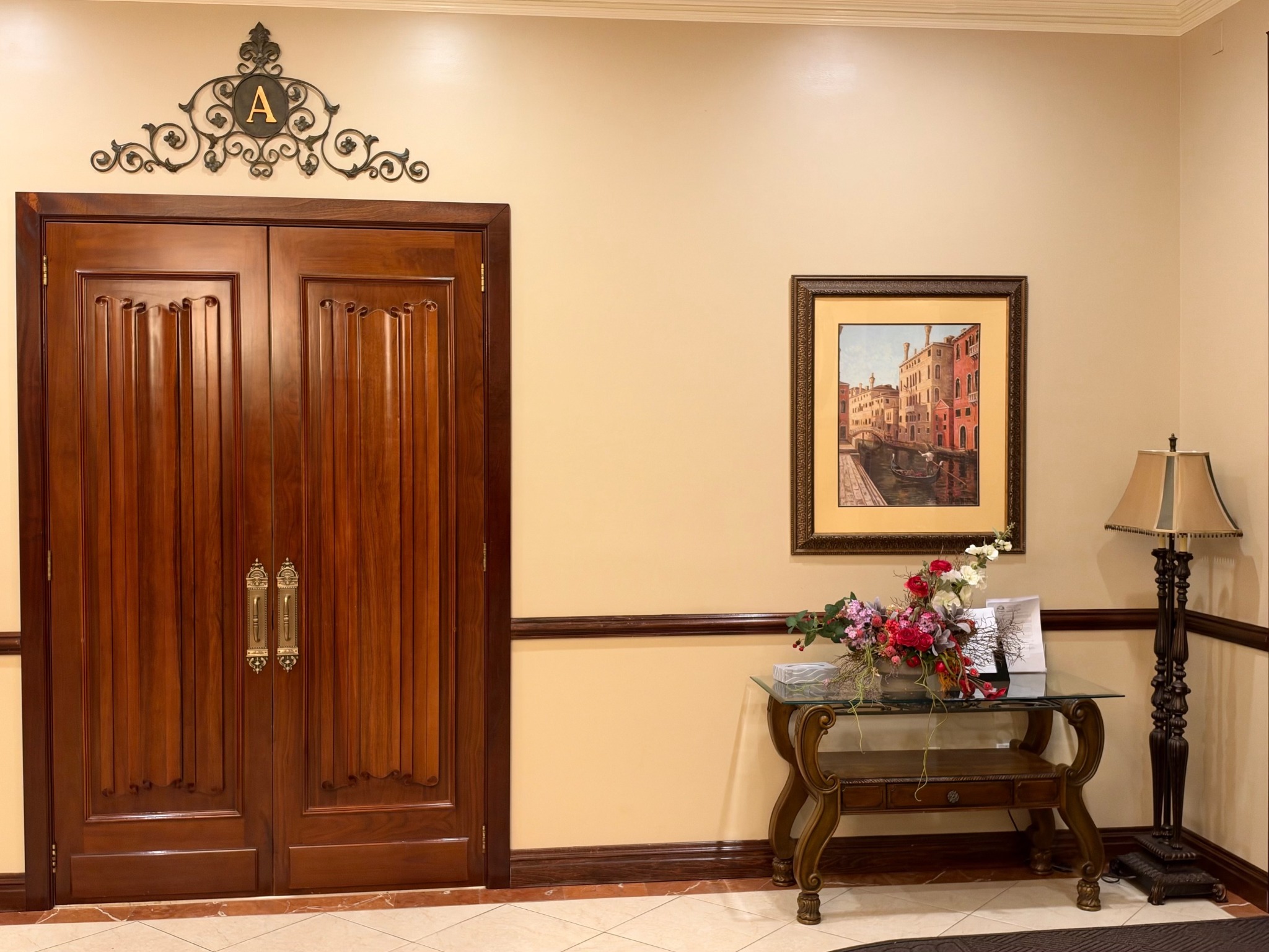 The entrance to Chapel A, with carved wooden doors, framed artwork, and flowers.